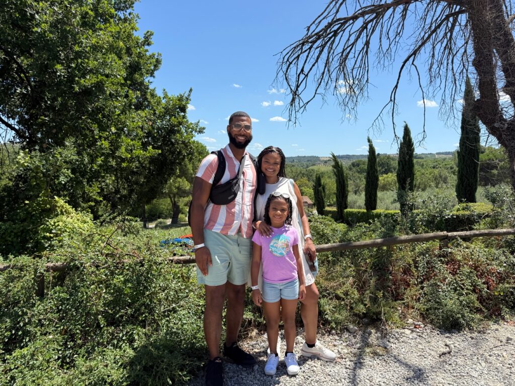 Family photo in the Tuscan countryside with cypress trees.